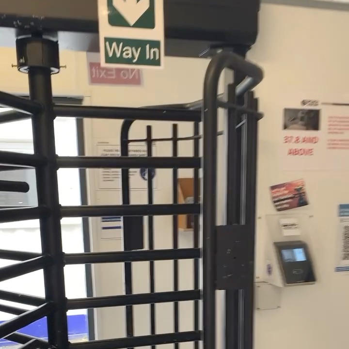 Site turnstile with a facial recognition terminal on the wall beside it