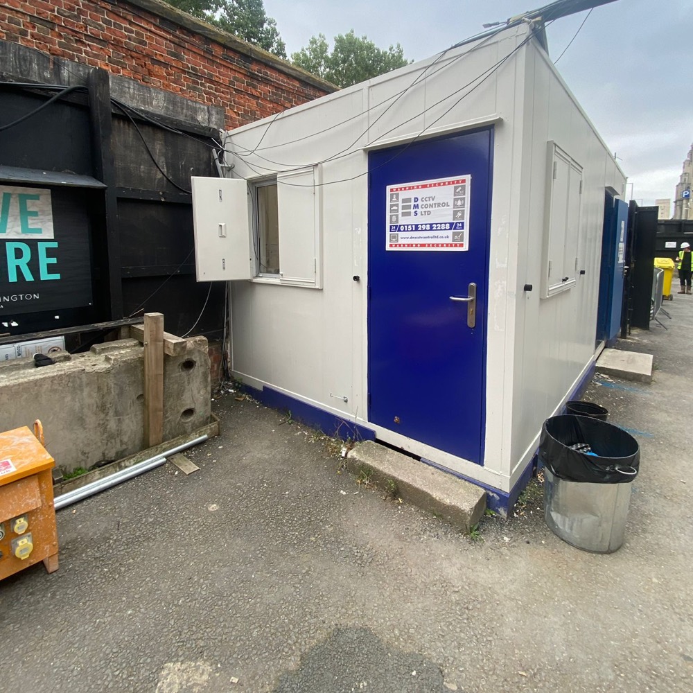 White site cabin with a blue door and DMS signage