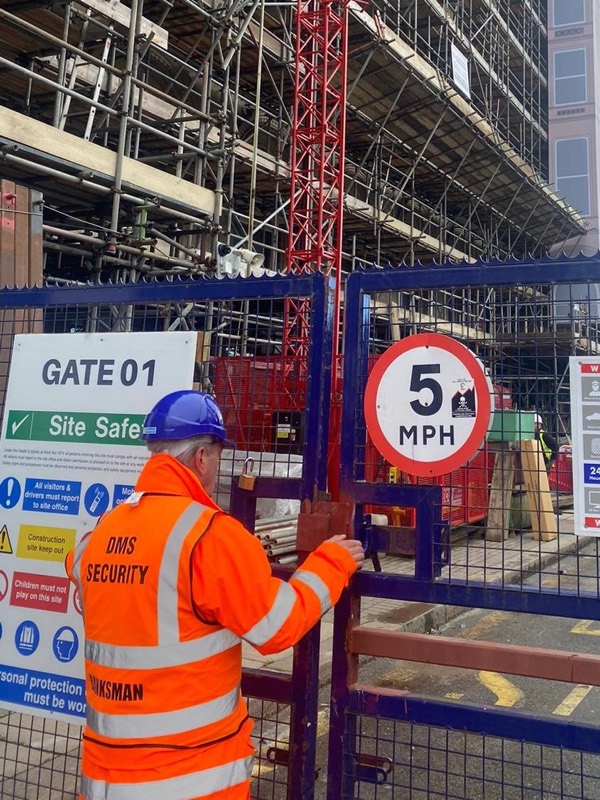 DMS banksman in hi-vis securing a site gate