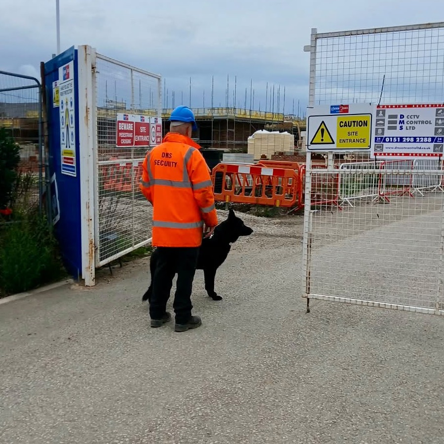 DMS dog handler in hi-vis with a guard dog at a site entrance