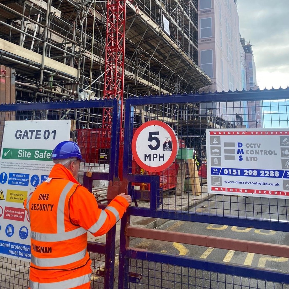 DMS officer in hi-vis securing a site gate beside DMS security signage
