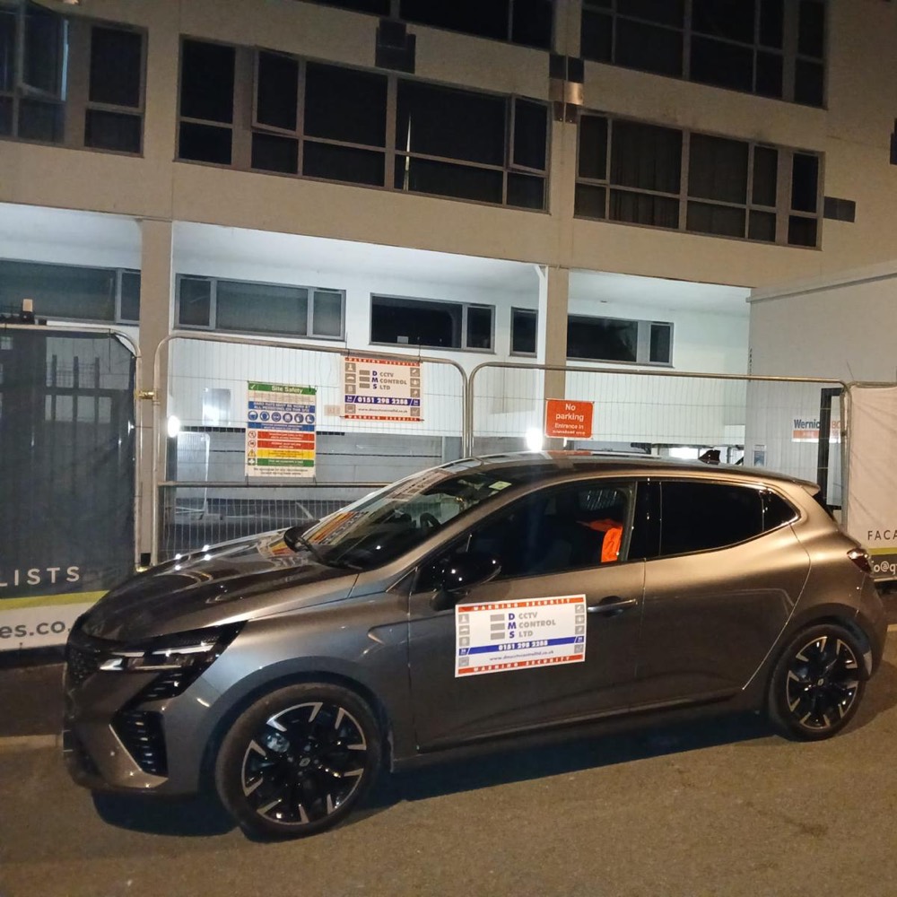 DMS patrol car with company signage outside a site at night