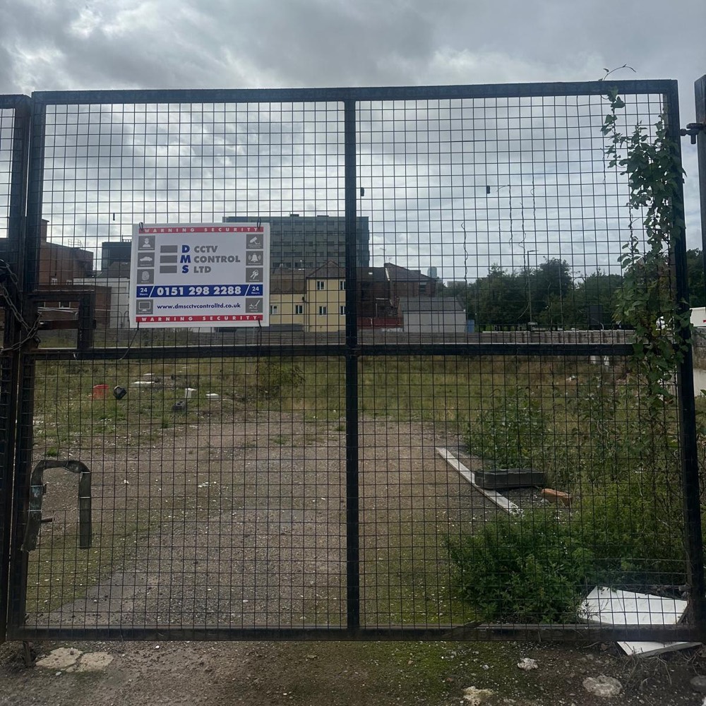 Locked gate with DMS signage at a vacant site